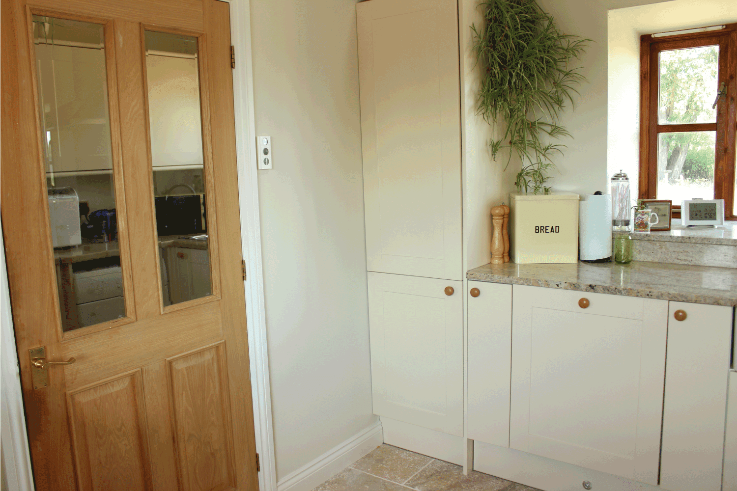 通风的乡村厨房，有松木后门雷电竞官网网址和震动派风格的橱柜，以及闪亮的花岗岩台面