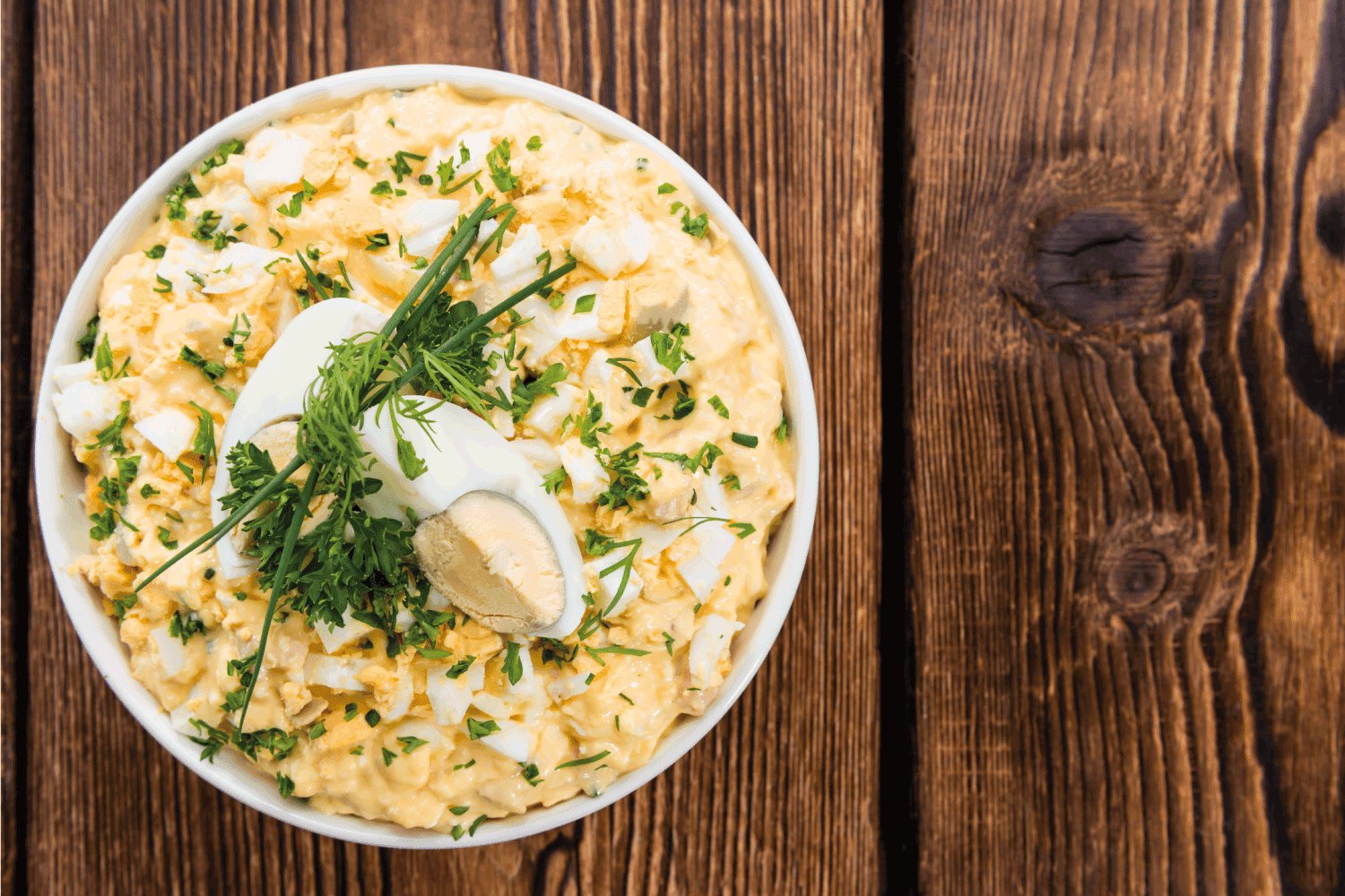 碗鸡蛋沙拉在黑暗的木制背景