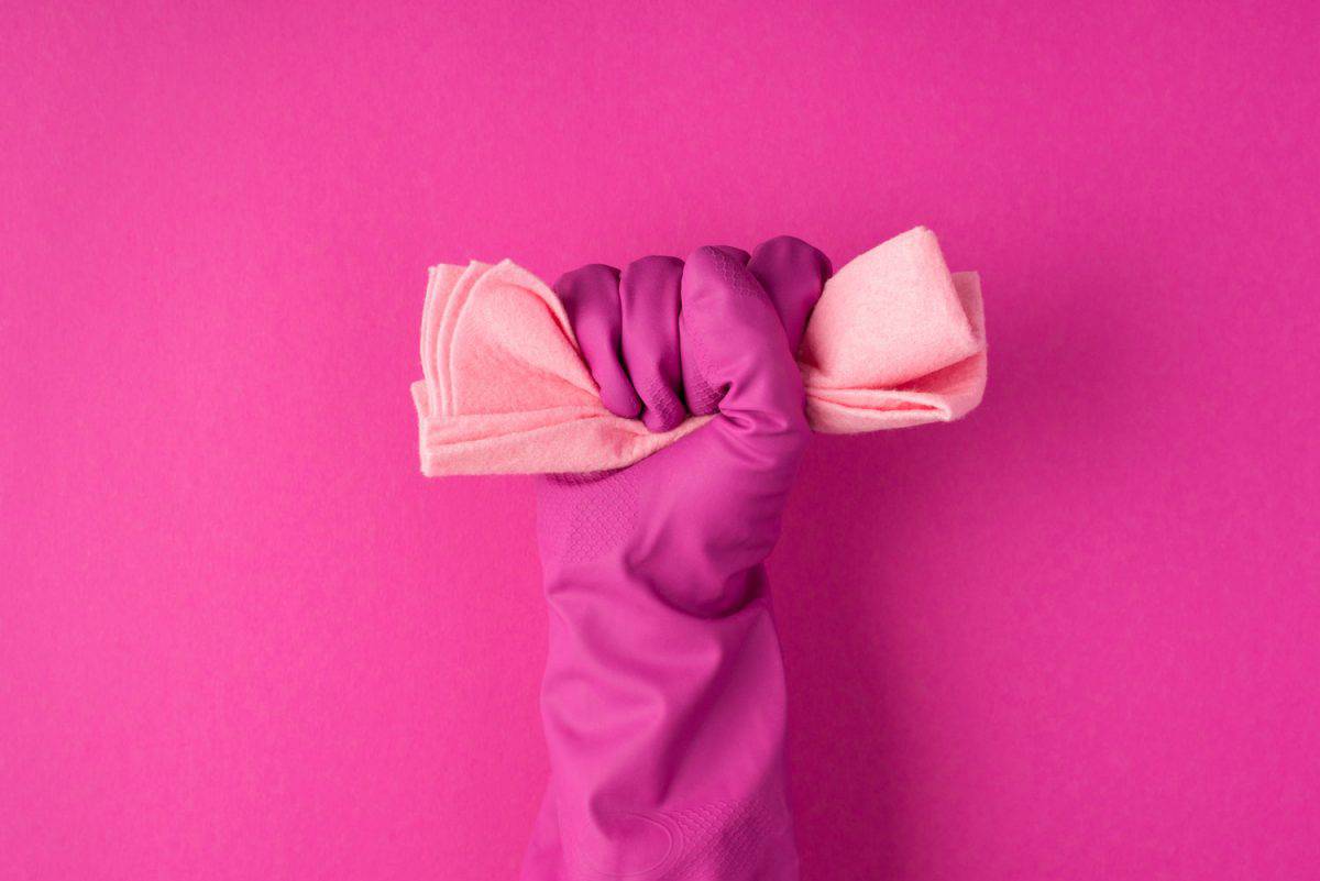 照片在粉红色手套举起手紧握粉彩粉红色抹布成拳头孤立的粉红色背景