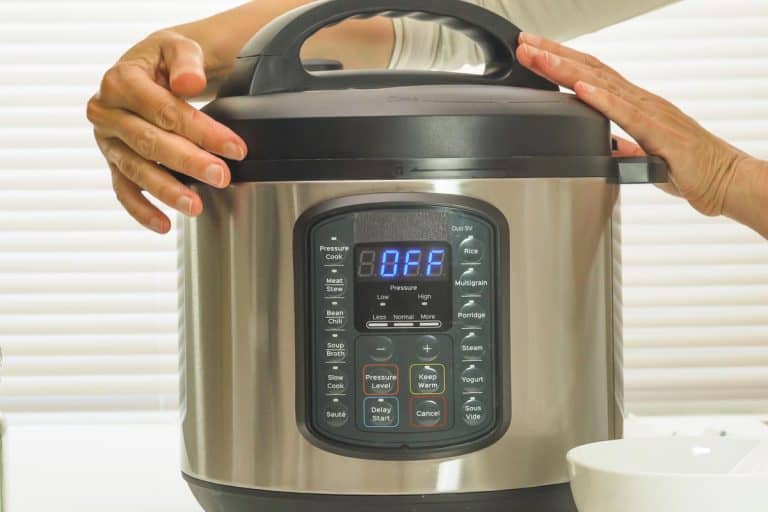 一个女人拿着餐桌上的高压锅,跨入压力锅保持关闭——要做什么?雷电竞官网网址