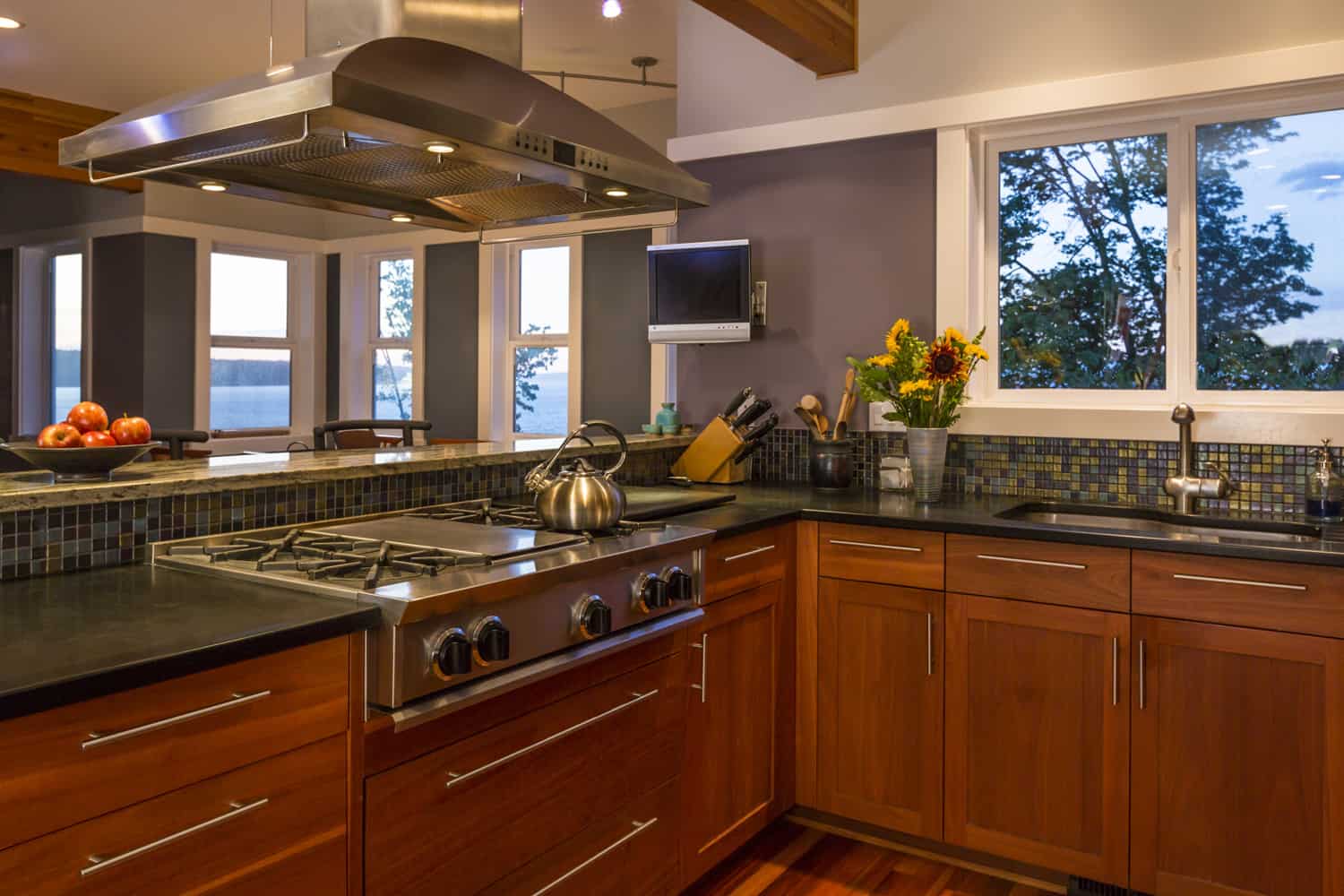 当代高档家庭厨房内部配备木橱柜，煤气炉，不锈钢通风罩雷电竞官网网址，混凝土台面，玻璃瓷砖后挡板和观景窗雷竞技官网rb