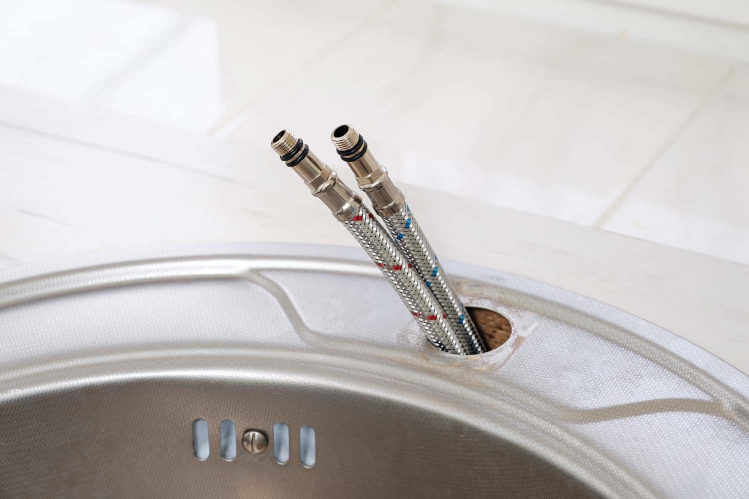 灵活的冷热自来水水软管在安装厨房的水龙头变成一个特写。雷电竞官网网址