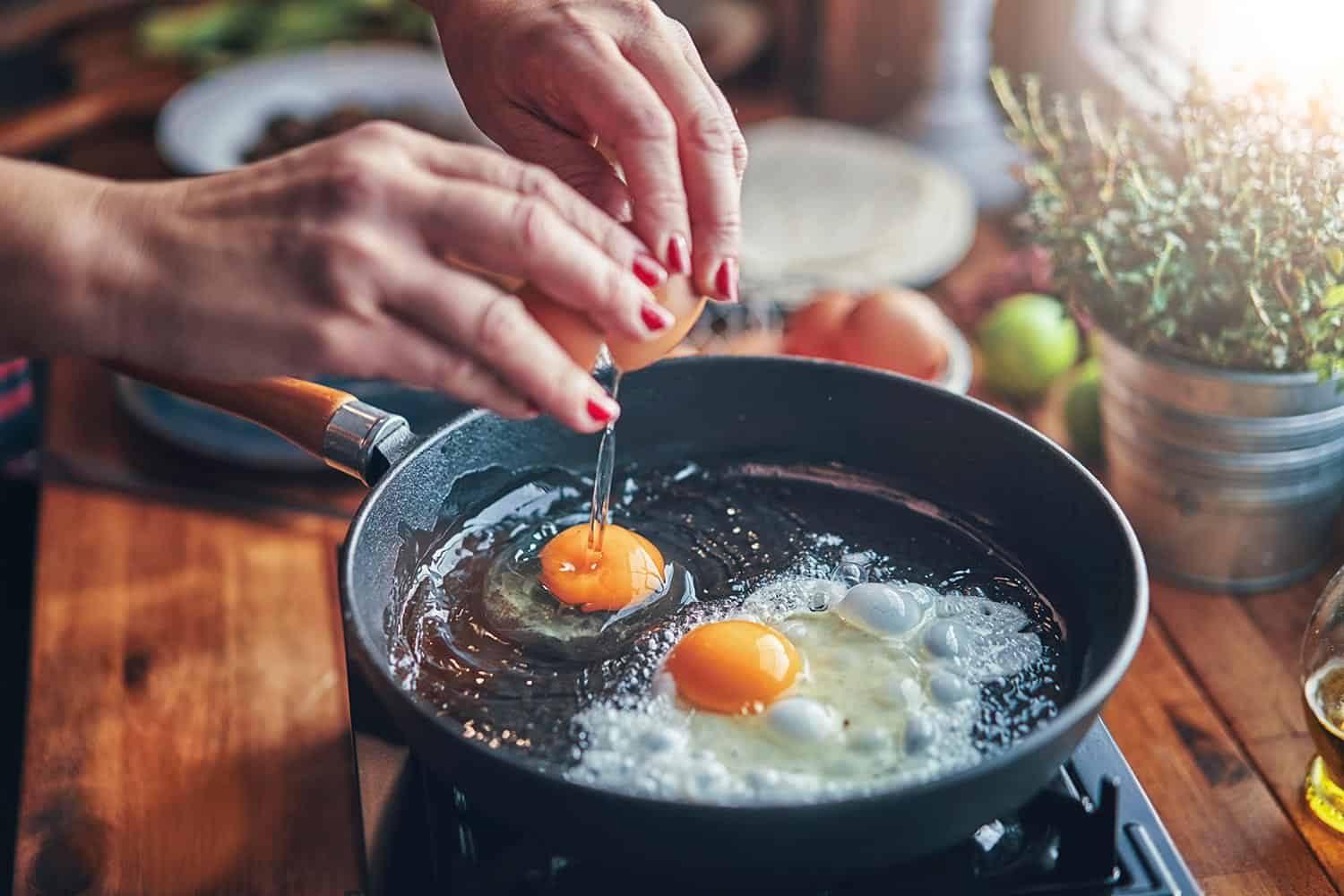 Frying egg in a cooking pan in domestic kitchen