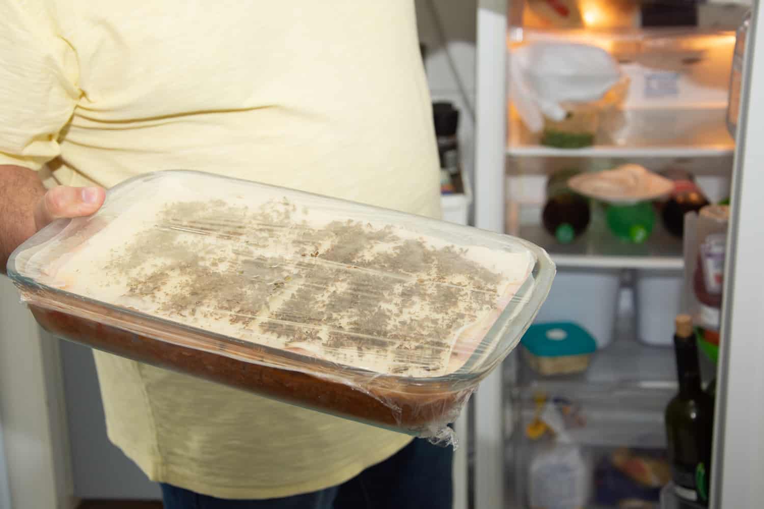 厨房里有个人从冰箱里拿雷电竞官网网址千层面