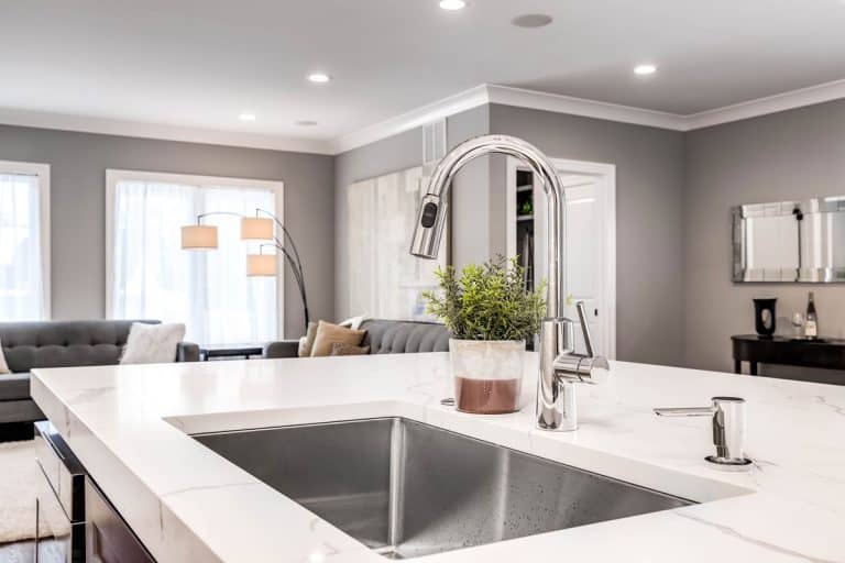 A kitchen sink in a luxurious home looking out towards a living room area, How to Tighten A Loose Kitchen Faucet Base
