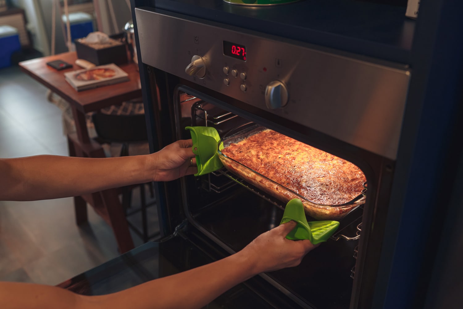 一双的手从烤箱获取新鲜出炉的烤宽面条