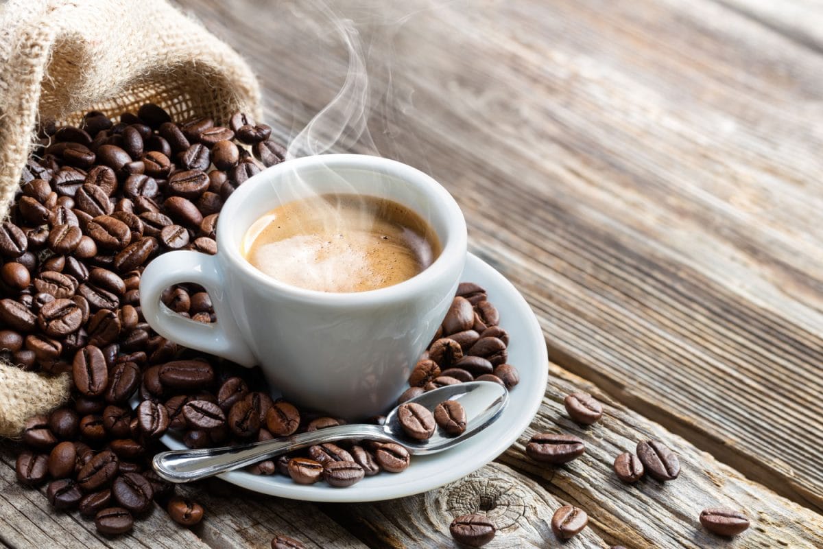 新鲜冲泡的咖啡用咖啡豆撒在桌上