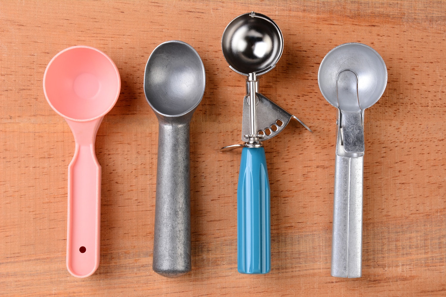 冰淇淋勺上的木头桌子。俯拍的四个不同的勺子。