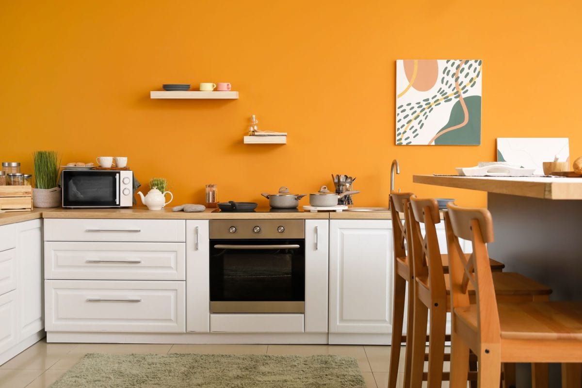 雷电竞官网网址厨房用橙色墙与白色的厨柜和木质台面