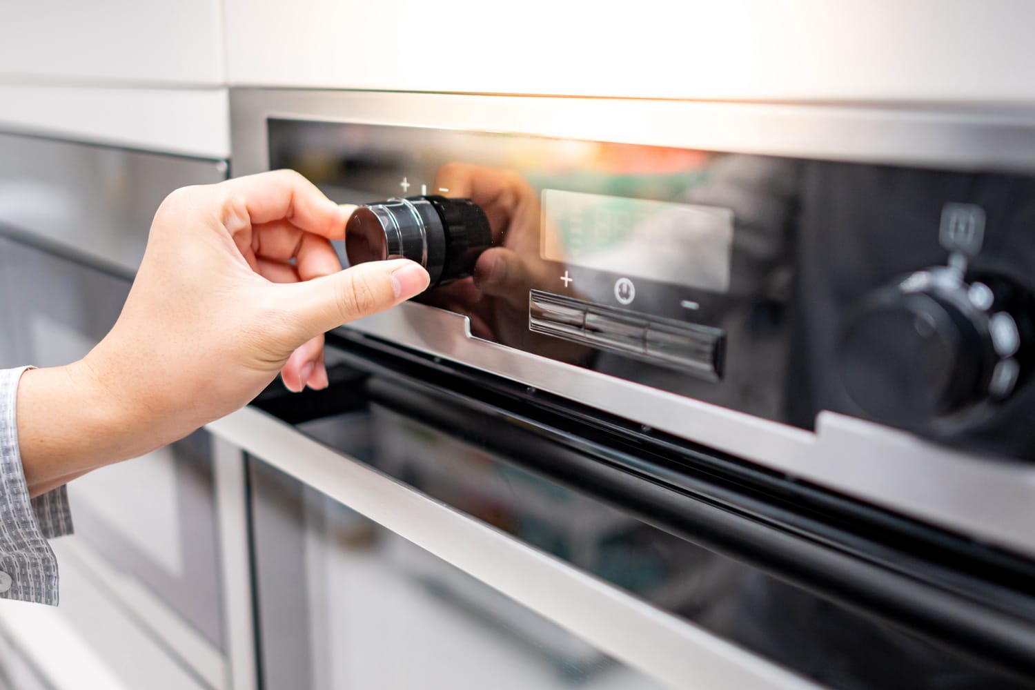 厨房陈列室现代烤箱的男性手动温度旋钮。雷电竞官网网址购买家用厨房炊具。雷电竞官网网址家居改善概念