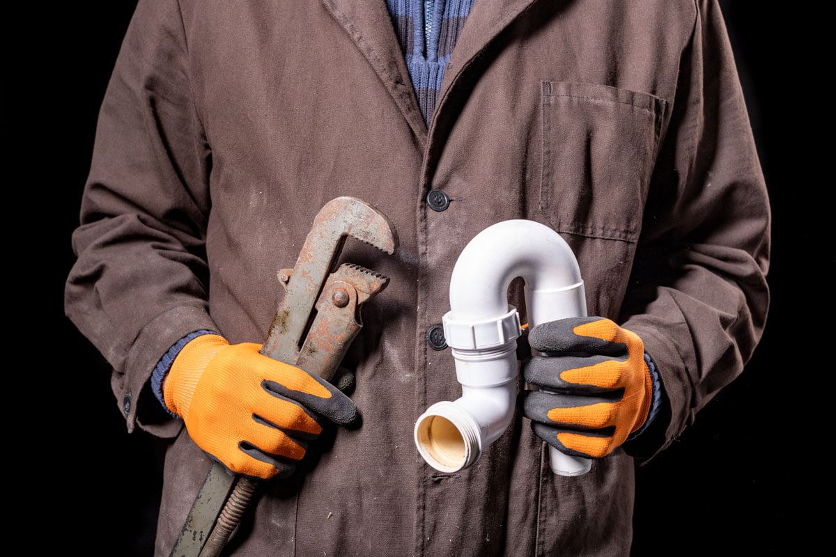 管道工拿着一个活动扳手和一个虹吸到洗脸盆