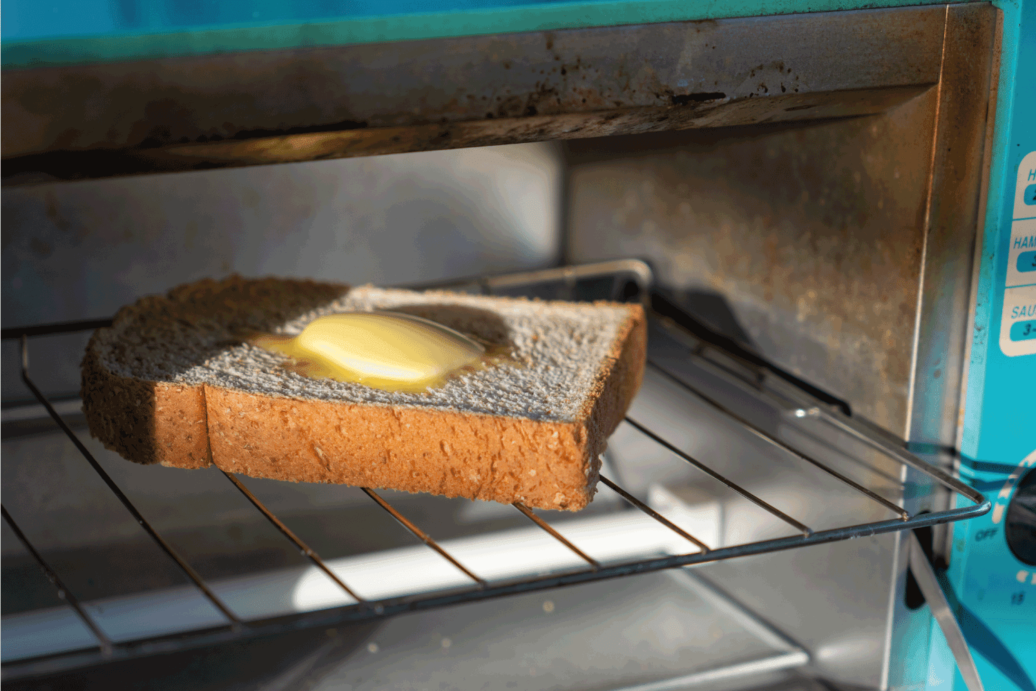 烤面包，全麦面包和黄油在电烤箱。＂width=