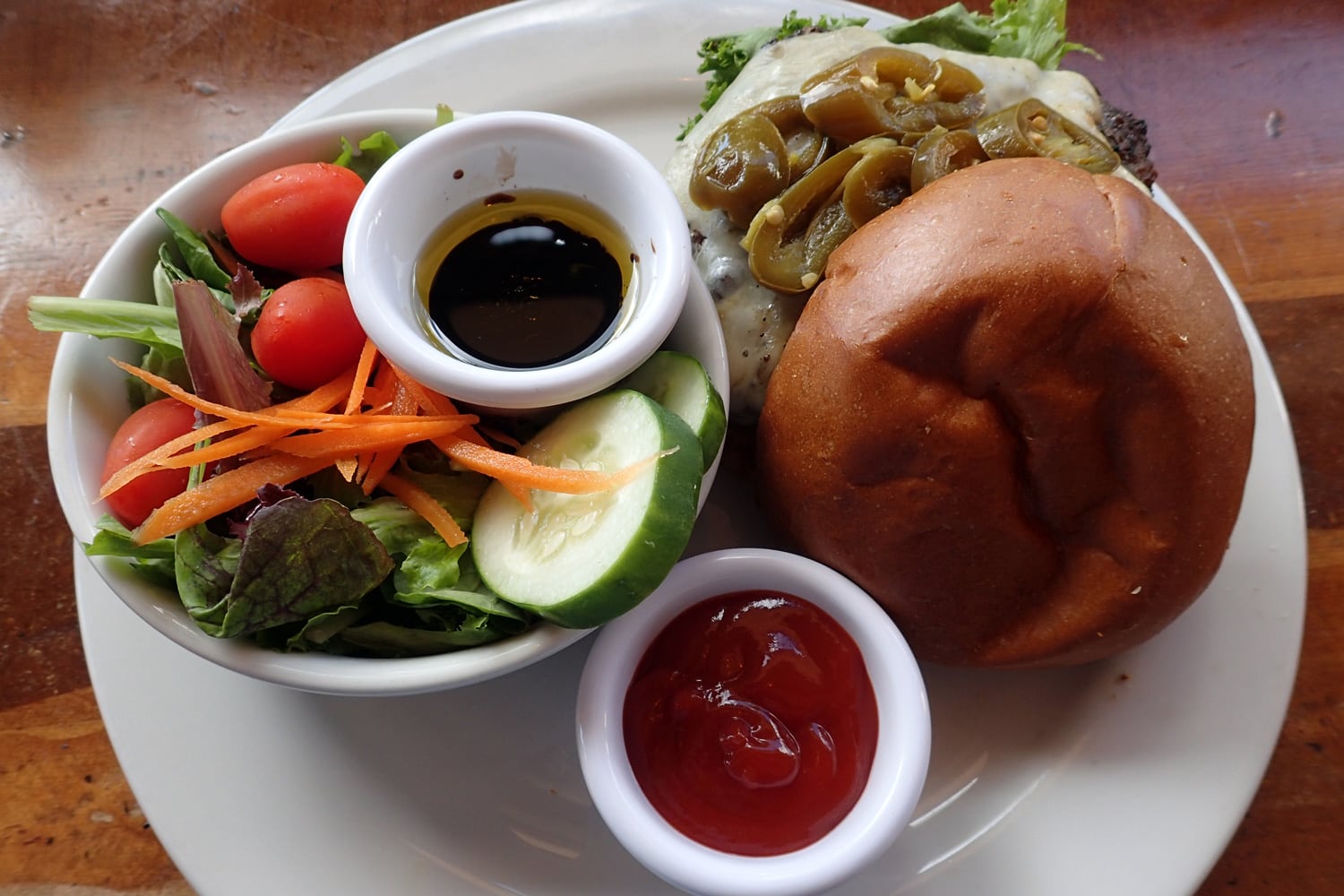 开封的墨西哥胡椒芝士汉堡配生菜、番茄、黄瓜、胡萝卜色拉，配油、醋和番茄酱。
