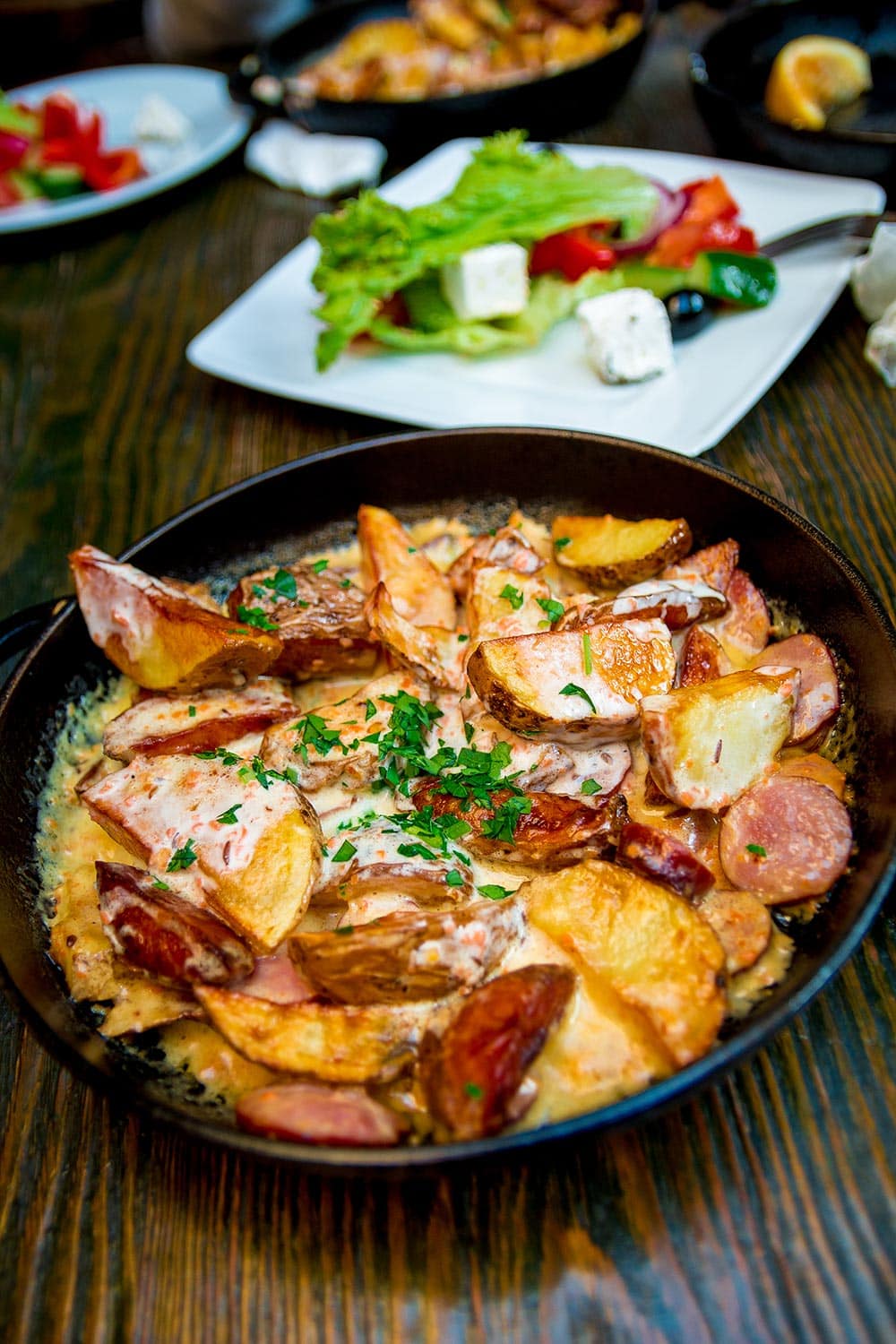 烤箱烤土豆奶油和奶酪在煎锅里黑色的木制的桌子上