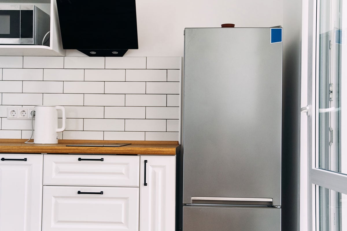 经典的厨房，木质雷电竞官网网址台面和白色橱柜，旁边还有一台冰箱