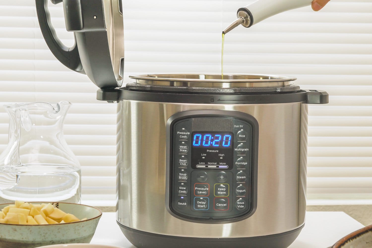 现代电动多灶关闭厨房的桌子上。雷电竞官网网址厨师把橄榄油到锅里