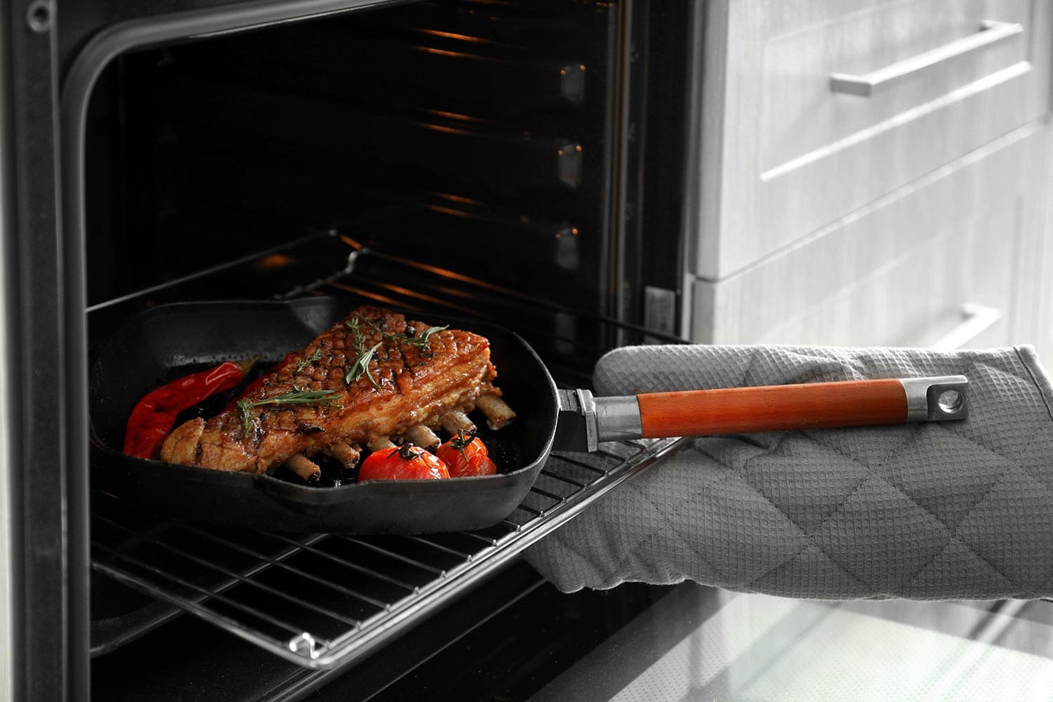 厨师把盛着美味烤排骨的平底锅从烤箱里拿出来