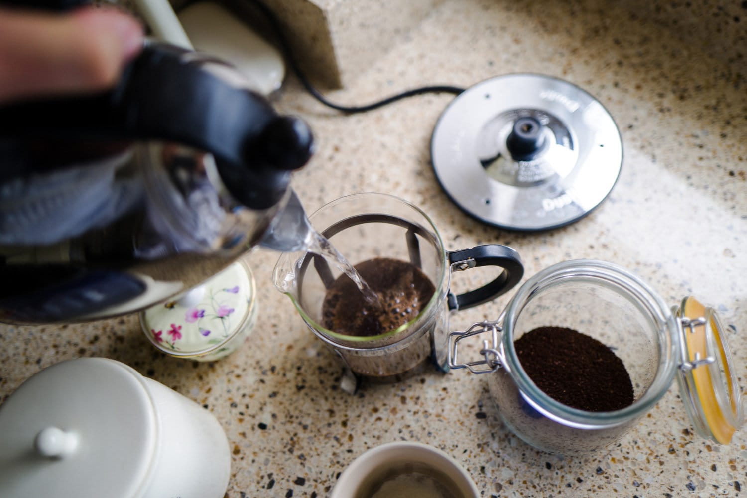 彩色图像描绘的人倒热水(不是沸腾)从一个水壶变成一个法国媒体充满了咖啡粉。