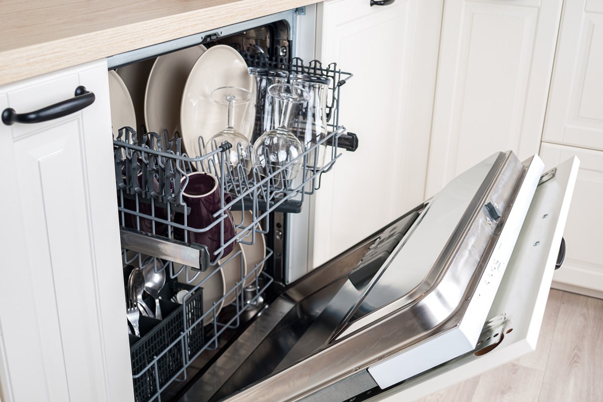 洗碗机开着，里面堆满了盘子和玻璃杯