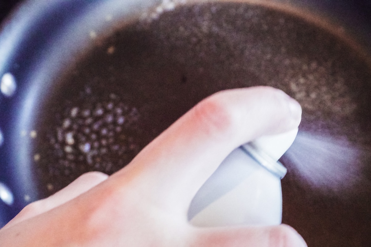Cook spraying a non stick skillet with cooking spray
