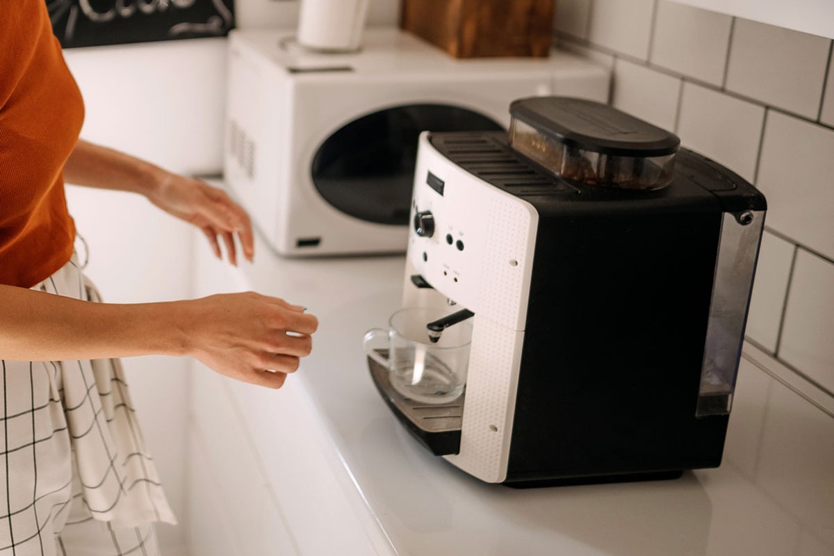 年轻女子在咖啡机煮咖啡在家里