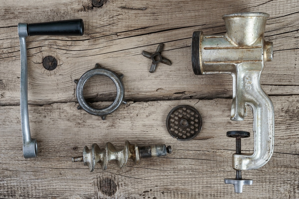 拆卸的手动绞肉机未装配的木桌上