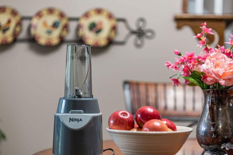 Ninja Juicer with bowl of apples on a table, Can I Shred Chicken In My Ninja Blender? [Yes! Here's How]