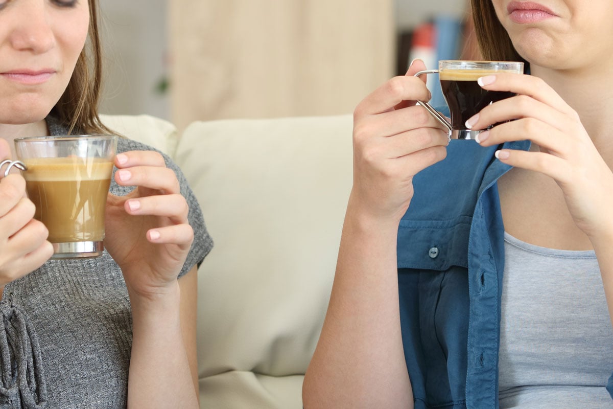 两个朋友喝咖啡与坏味道sititng在家在客厅沙发上