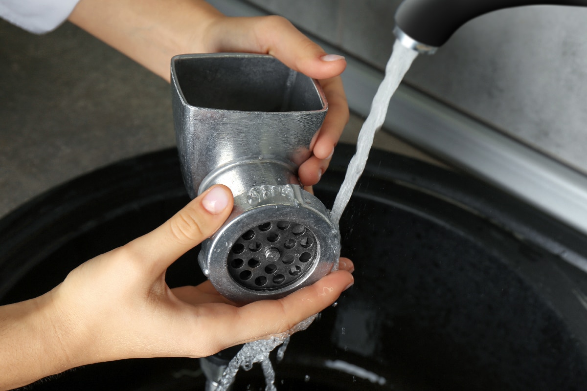 女人在自来水下冲洗手动绞肉机厨房水槽在室内雷电竞官网网址