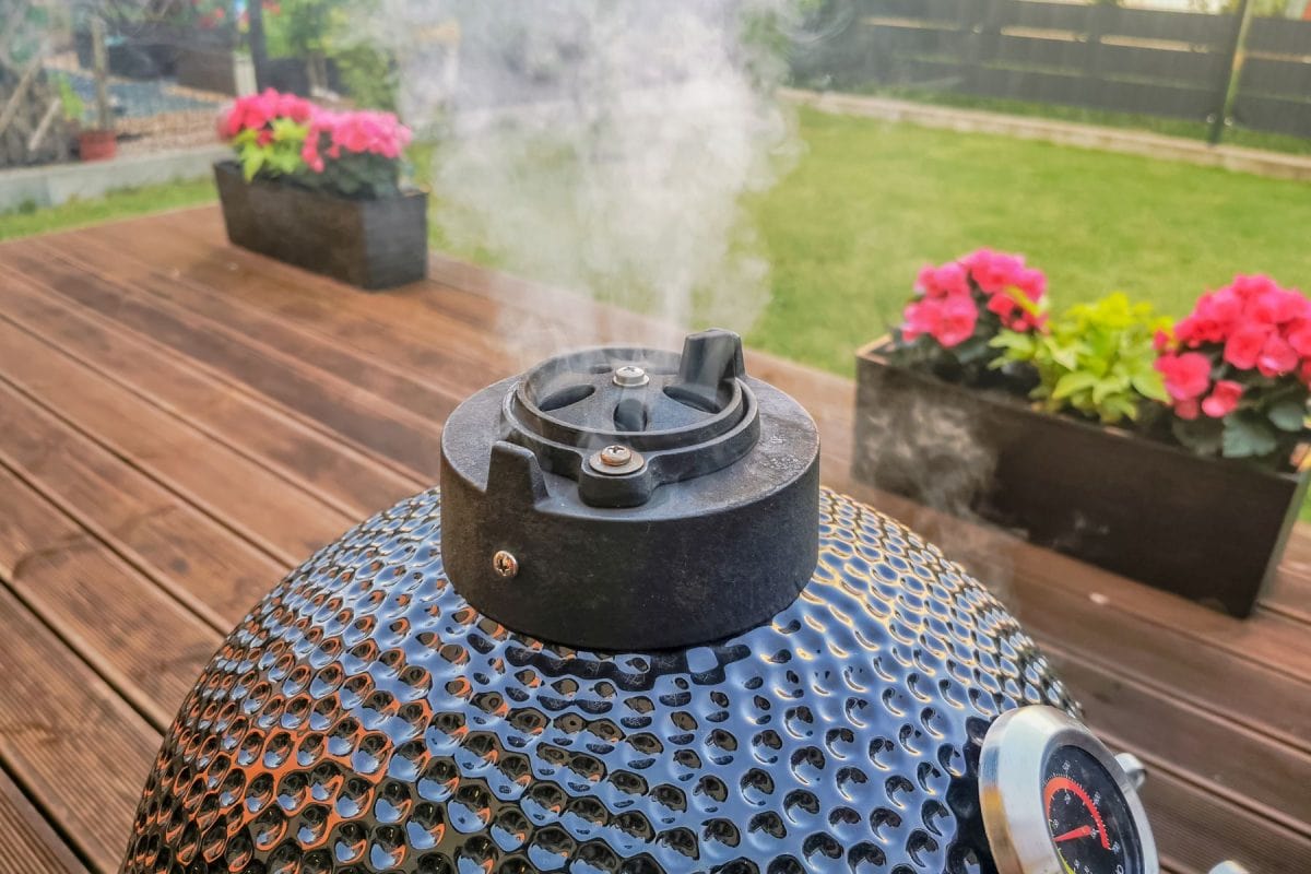 kamado蛋式烧烤烤架站在住的房子阳台烟从烟囱,用作冷烟的房子