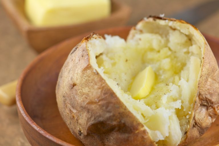 Baked potato with melted butter and freshly ground pepper in wooden bowl - Why Is My Baked Potato Hard