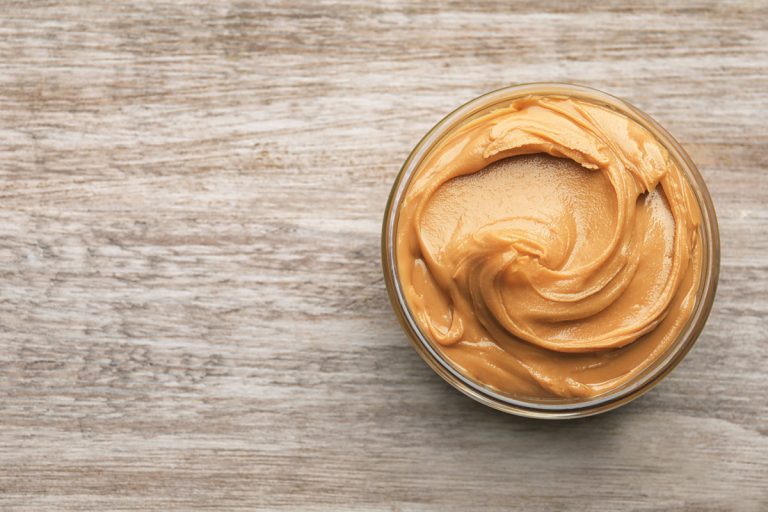 Glass bowl with peanut butter on wooden, What's The Difference Between Peanut Butter & Peanut Butter Spread?