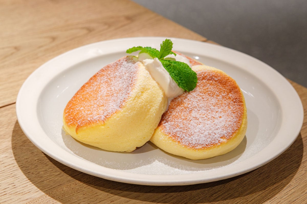 日式松饼甜点加奶油，放在白色盘子里，放在木桌上