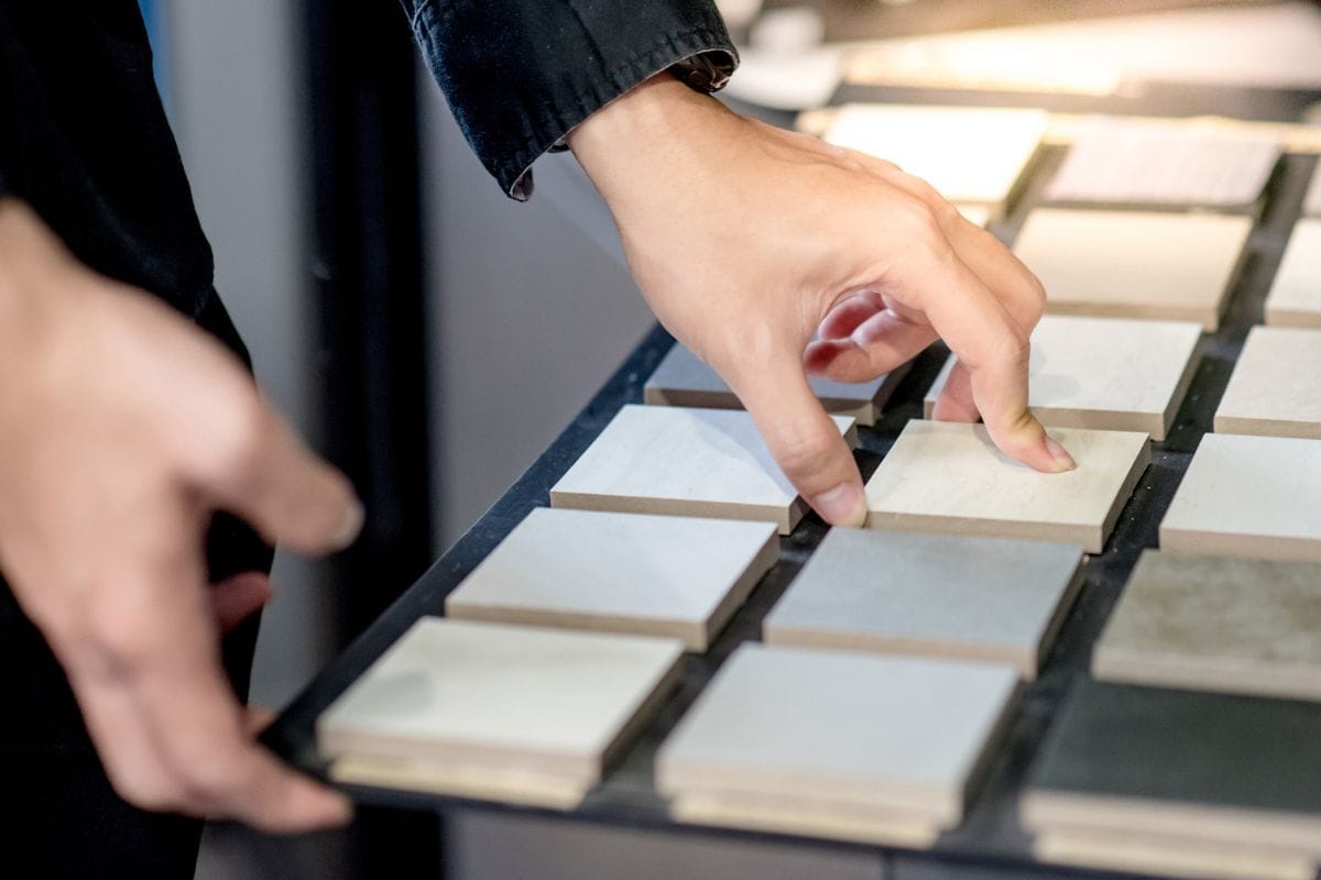 男性建筑师或室内设计师在设计工作室从样板板上手工挑选陶瓷纹理样品。建筑和建筑行业的地板和墙壁装饰材料。