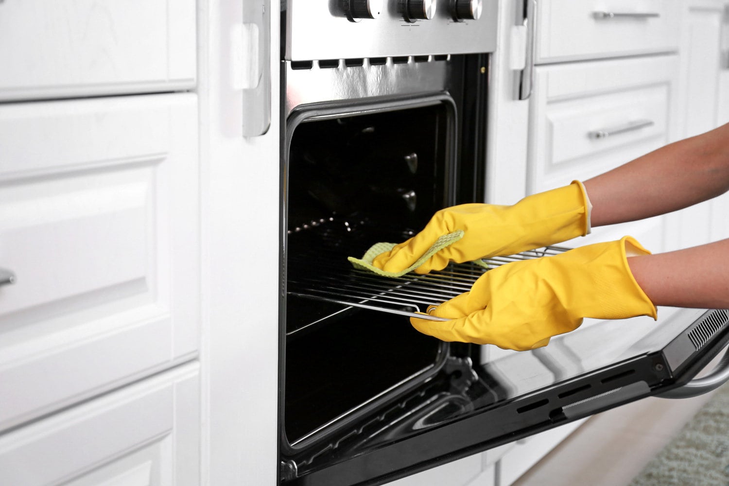 Woman cleaning oven in kitchen