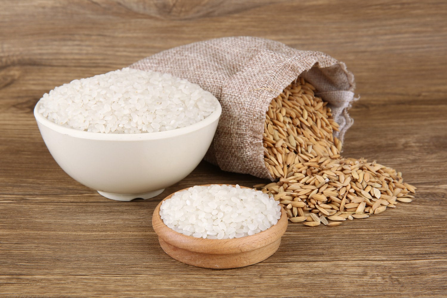 大米装在袋子里，米堆在木头背景上