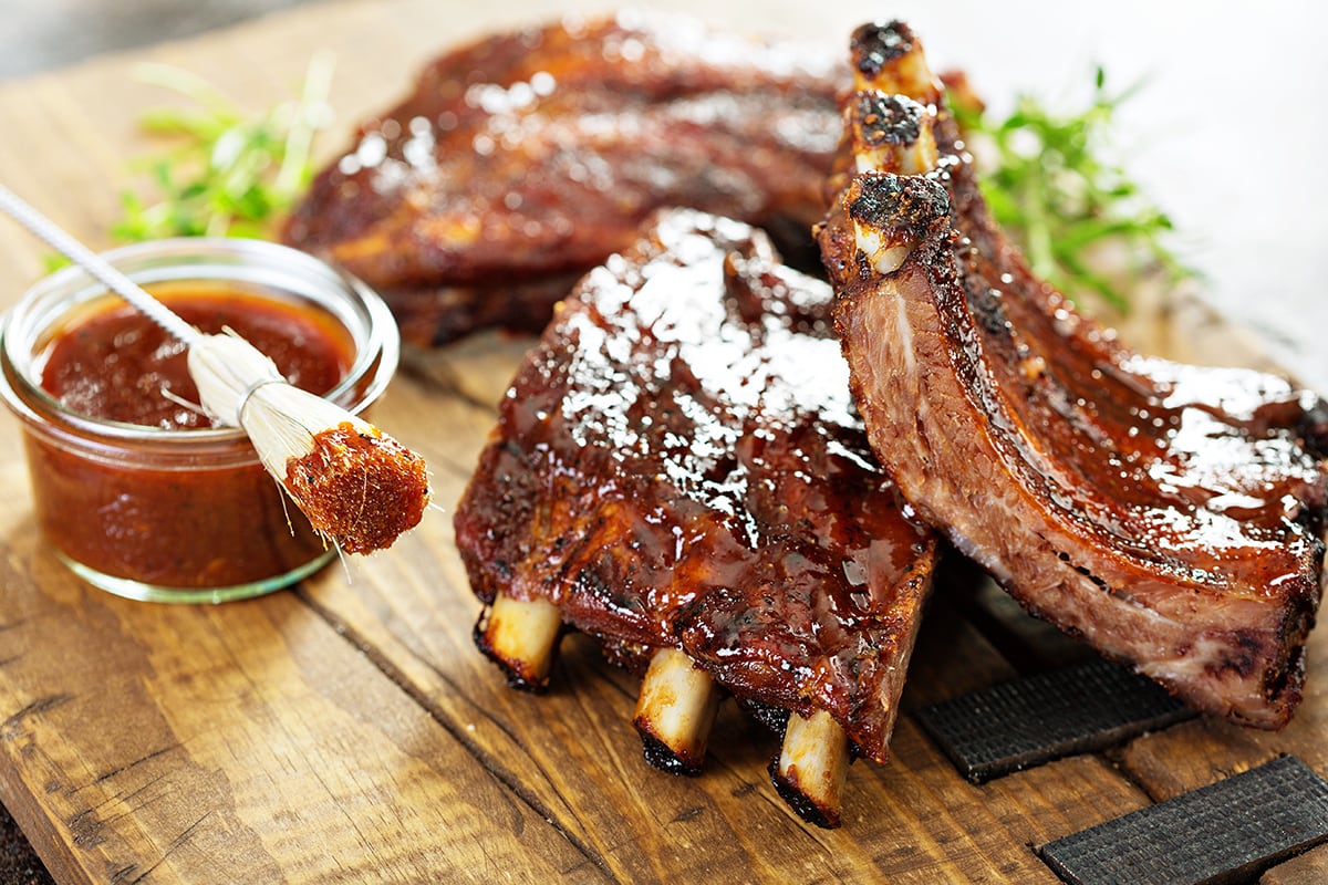 Grilled and smoked ribs with barbeque sauce on a carving board