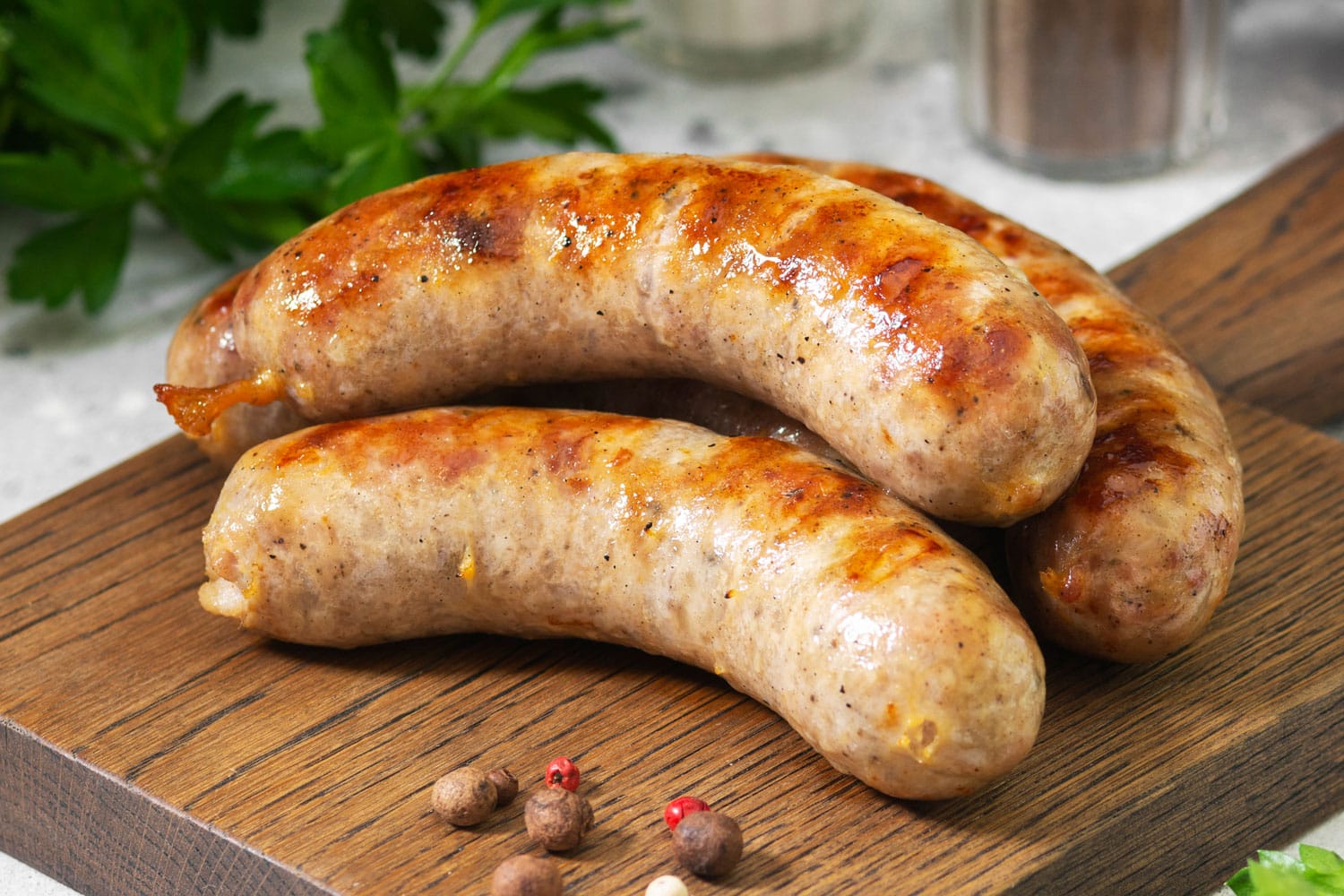 Grilled sausages on a wooden Board on a light gray kitchen table