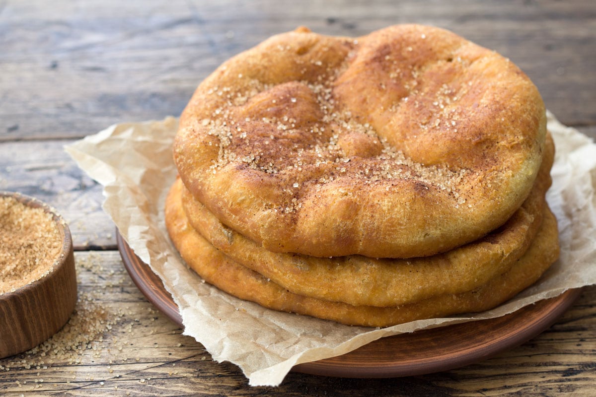 自制的纳瓦霍炸面包或甜象耳，配红糖和肉桂，放在木桌上