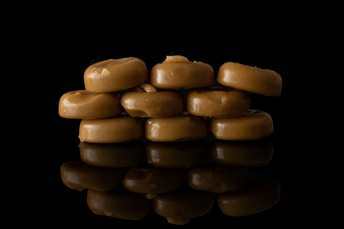 很多全焦糖棕色糖果孤立在黑色玻璃