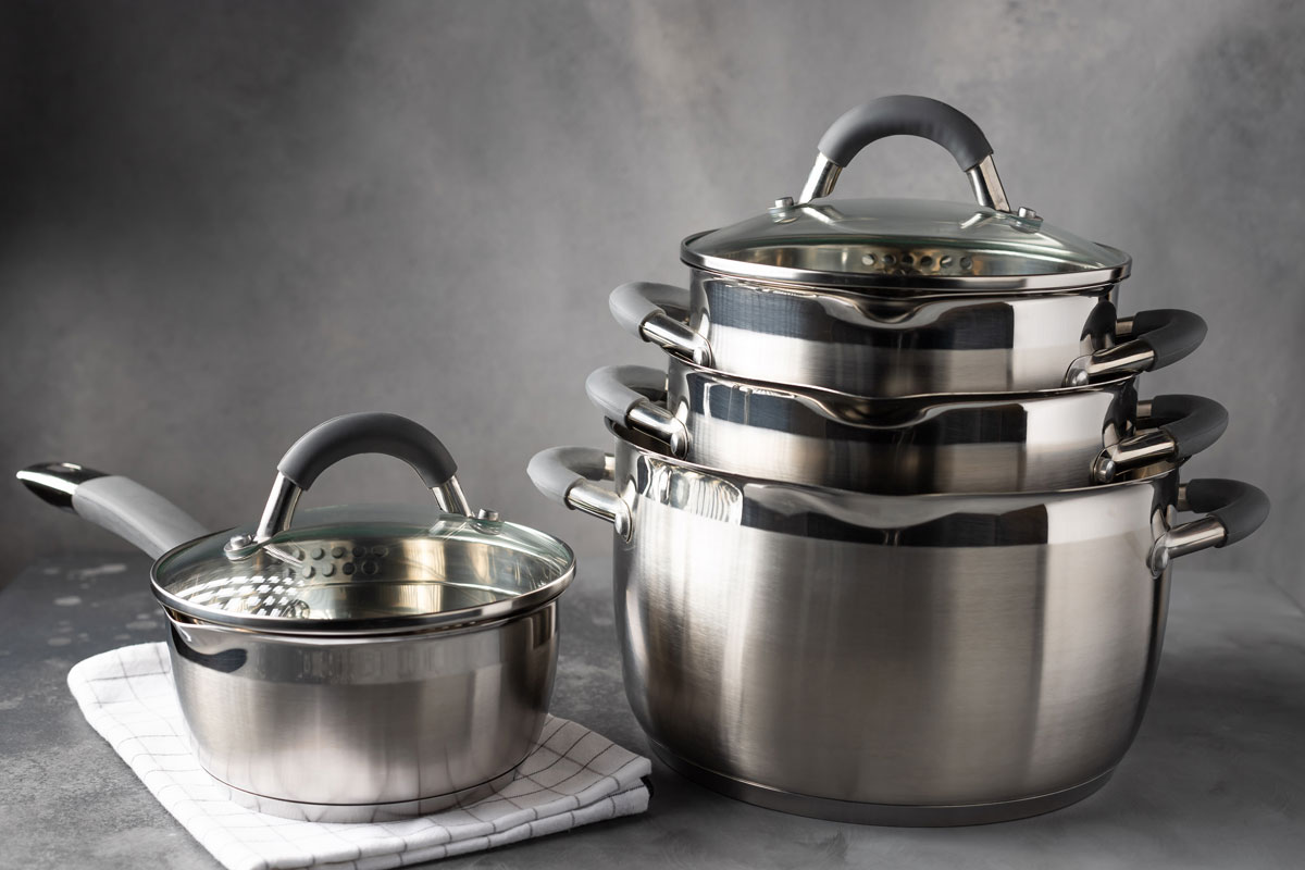 Stainless steel kitchenware against dark gray background. New cooking utensils.