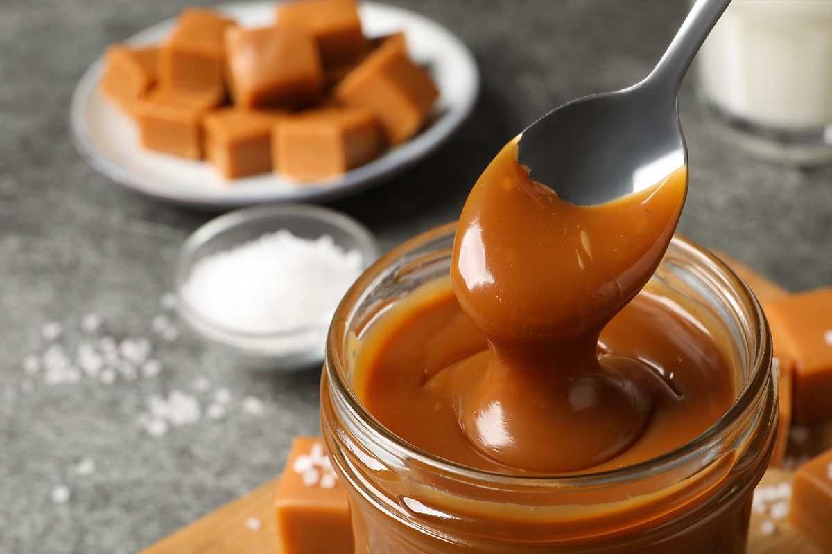 用勺子从桌上的玻璃罐里拿奶油糖果