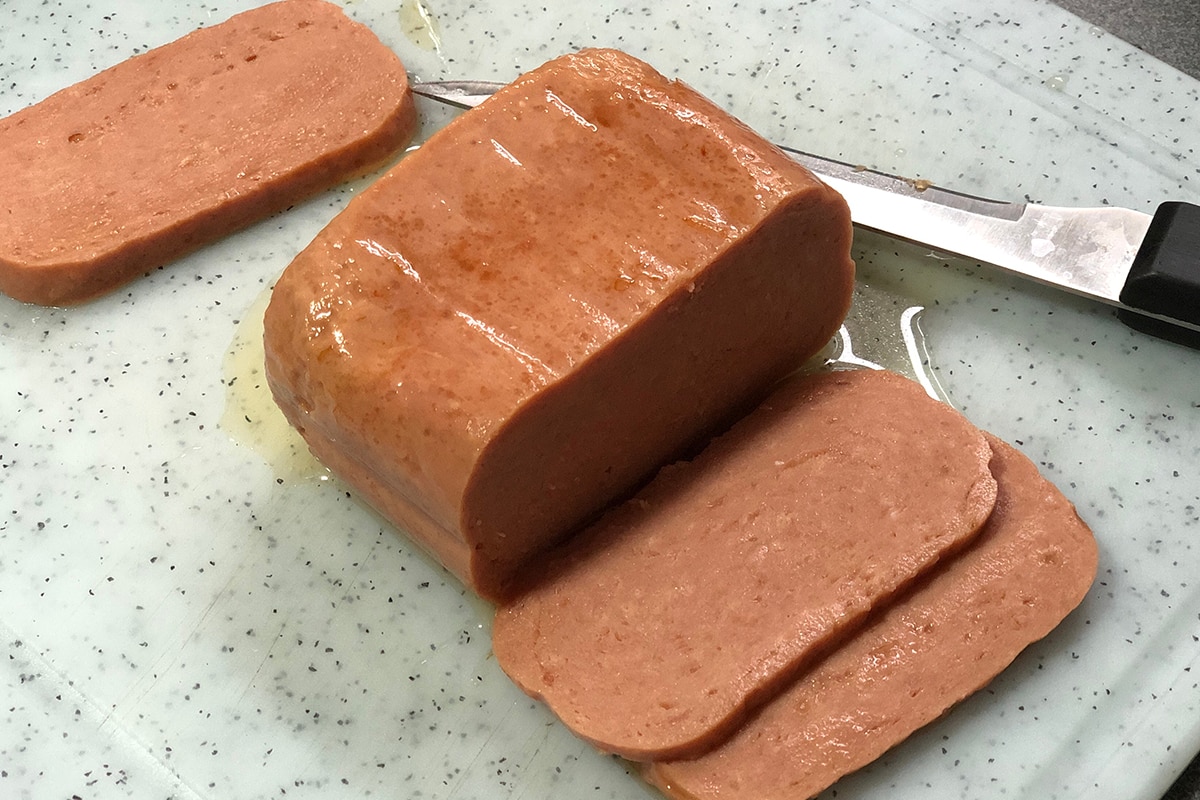 一块午餐肉，切成薄片放在砧板上＂width=