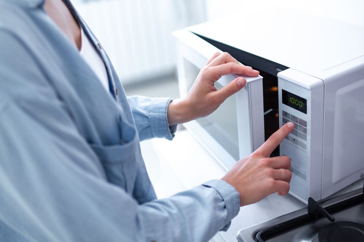 人变暖的食物在微波炉在厨房吃午饭在家里。雷电竞官网网址用微波炉加热食物。