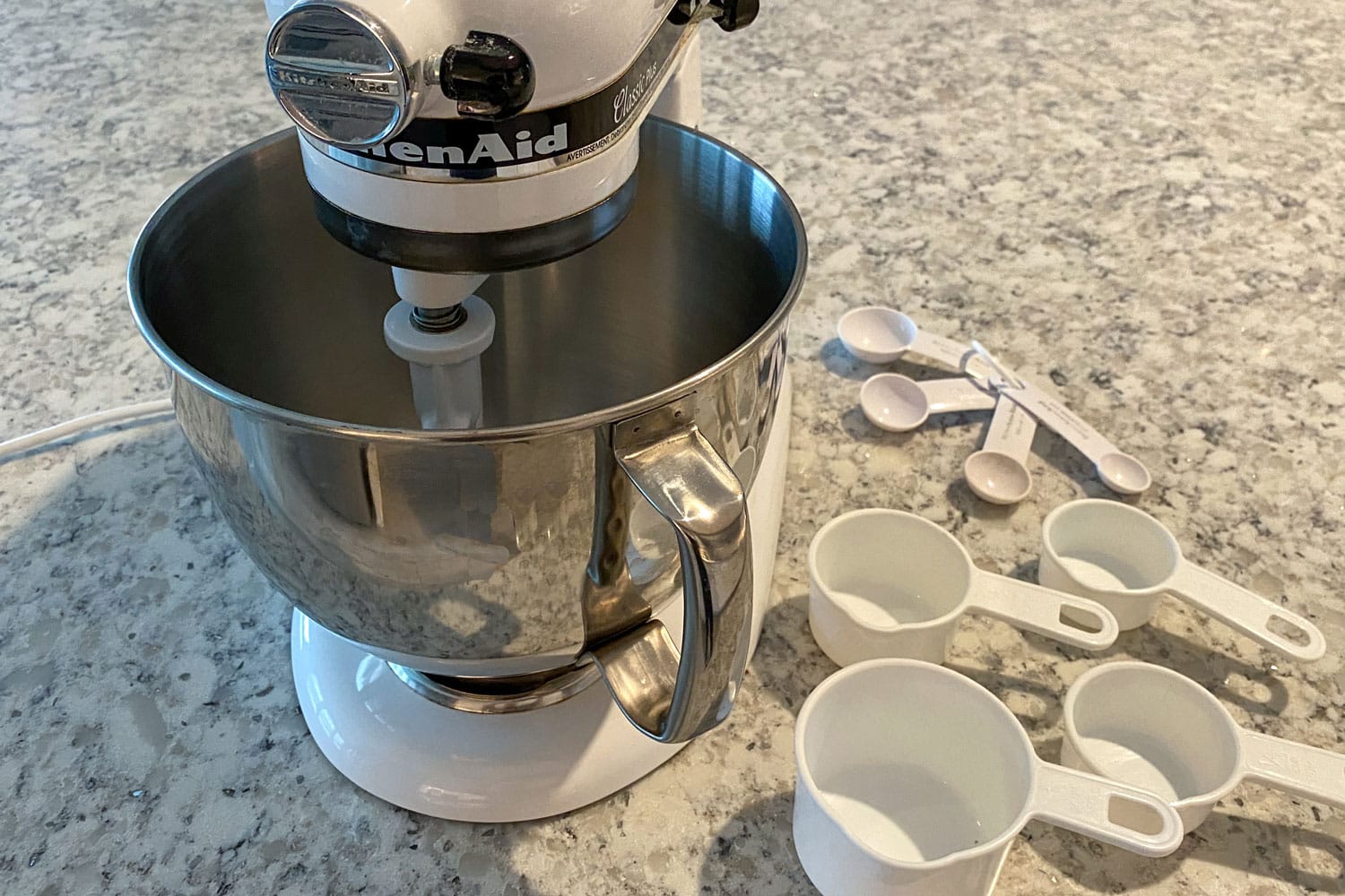 雷电竞官网网址厨房助手混合器在厨房柜台测量坐在它旁边的杯子和勺子。