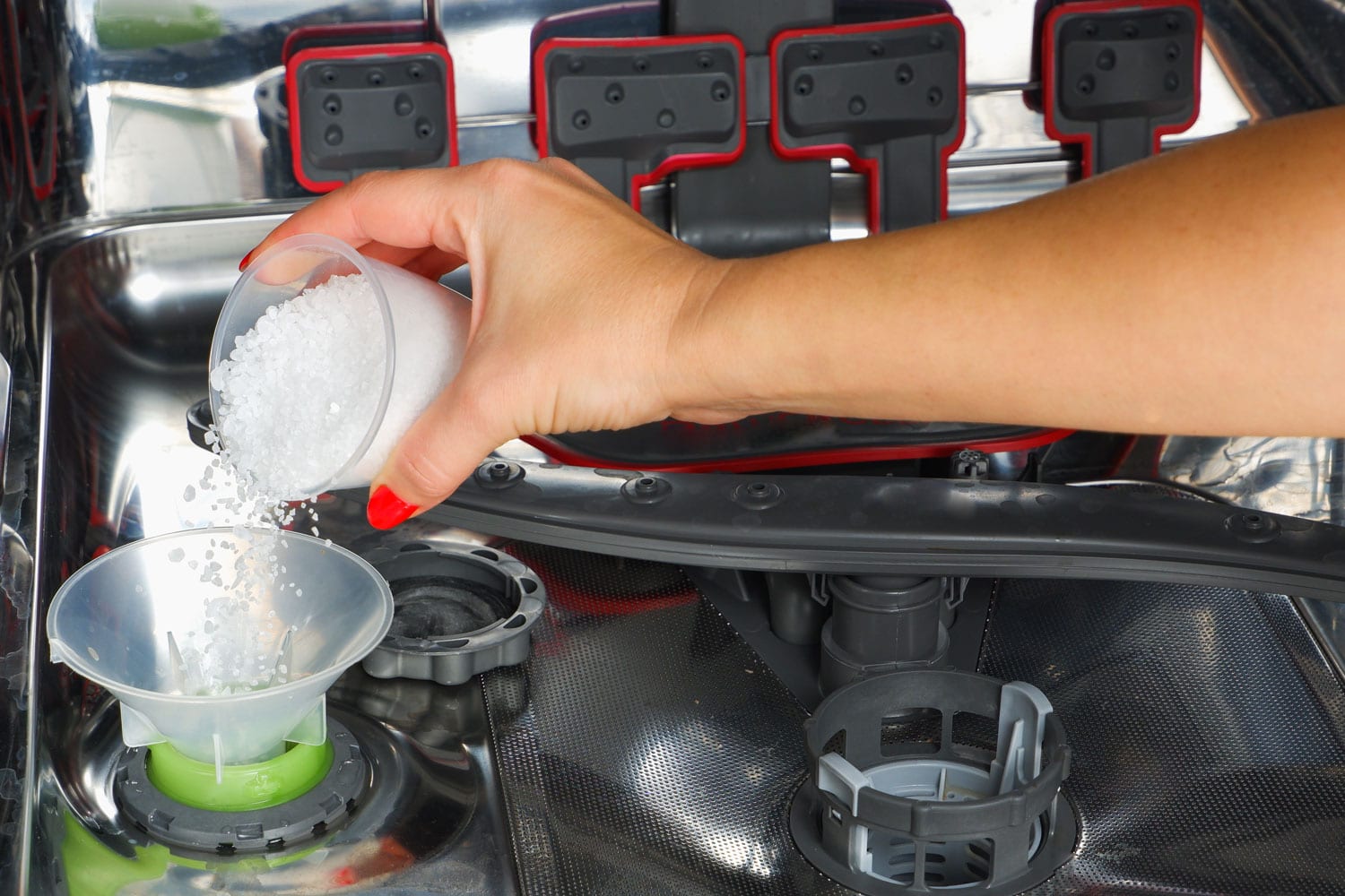 一个女人的手把盐软化水倒进洗碗机